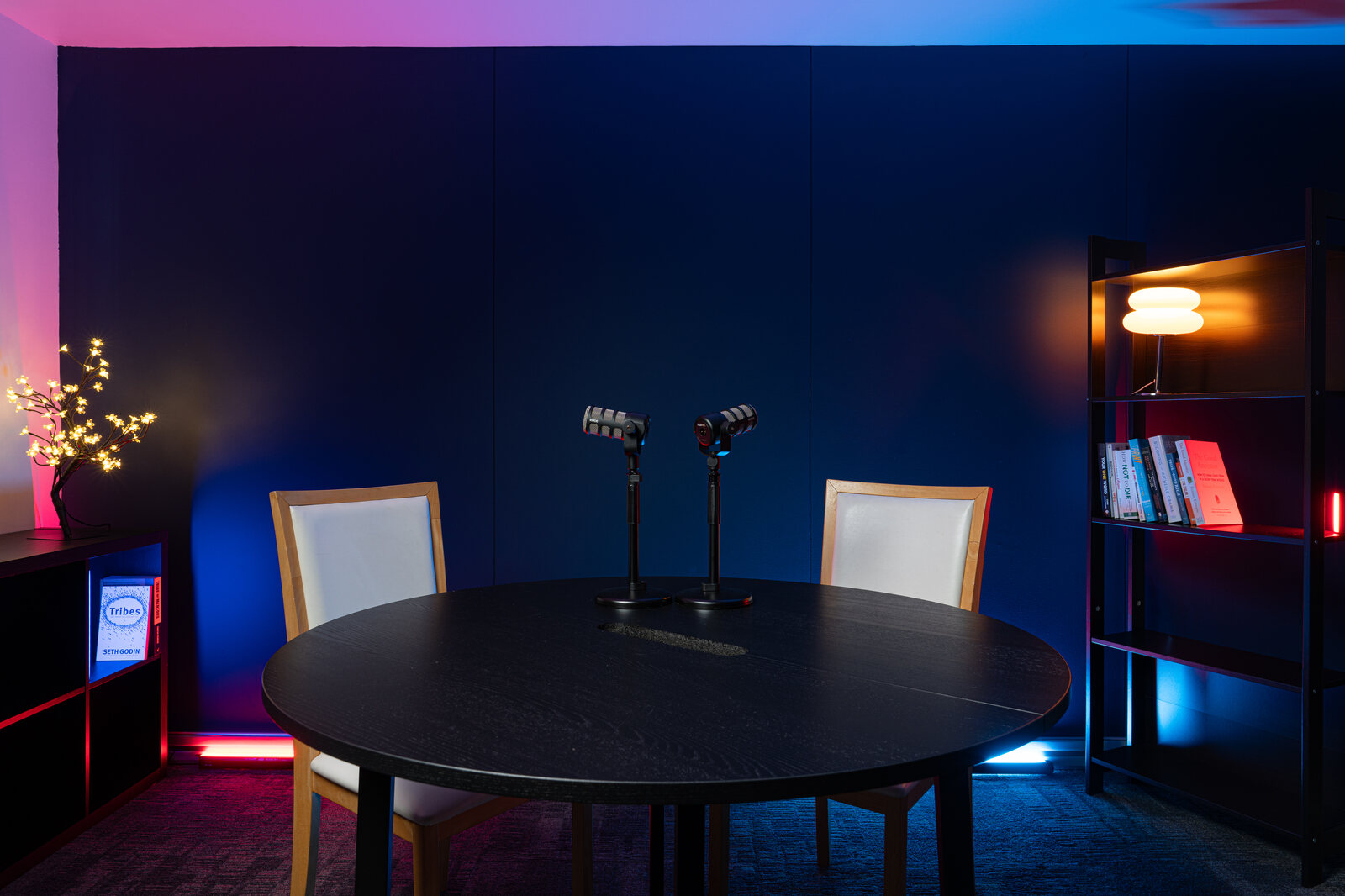 Paris set: a round black table with microphones against a navy acoustic wall