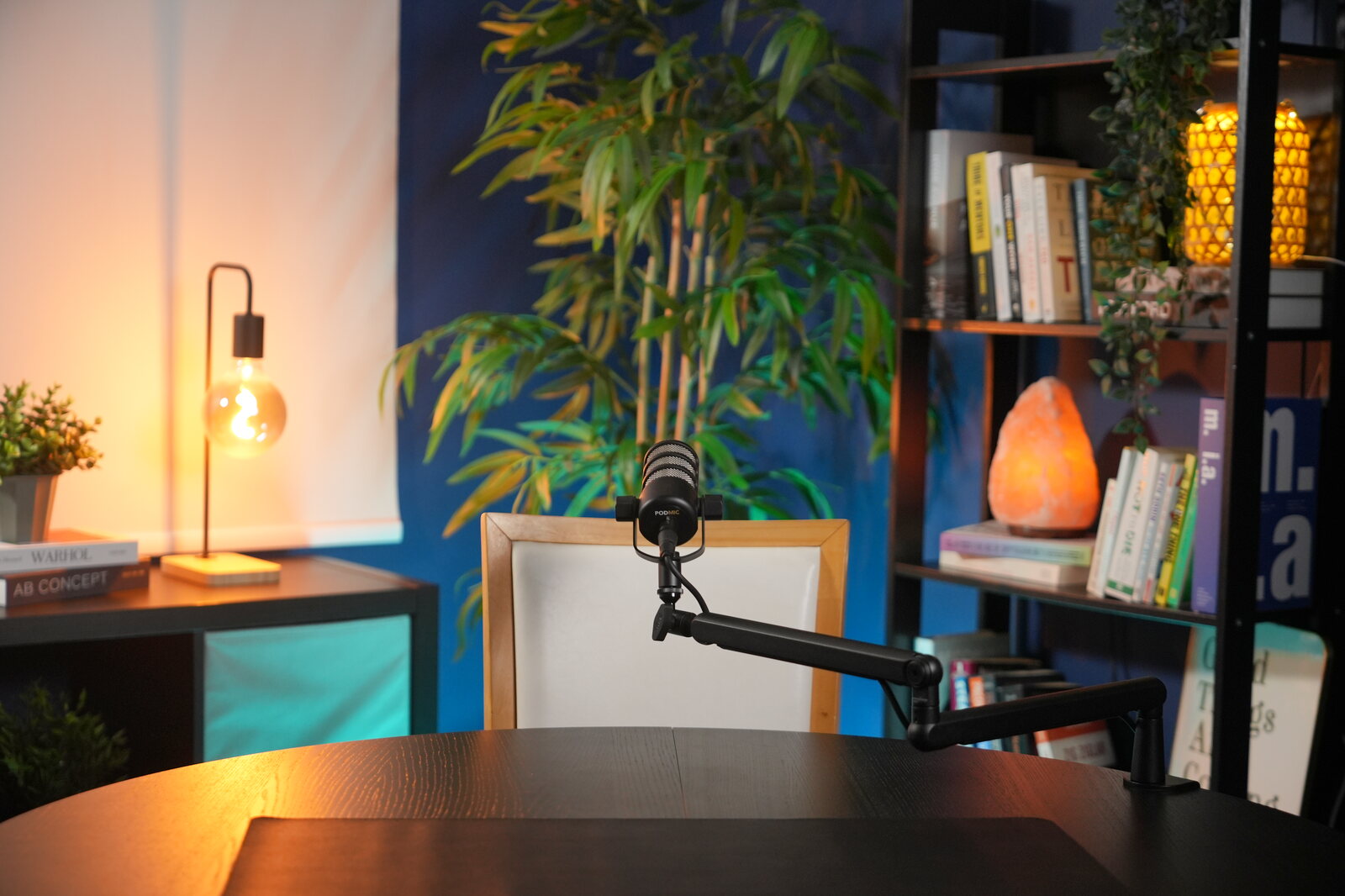 Shanghai set: a broadcast microphone on a dark desk against a deep blue backdrop, warm lamp behind