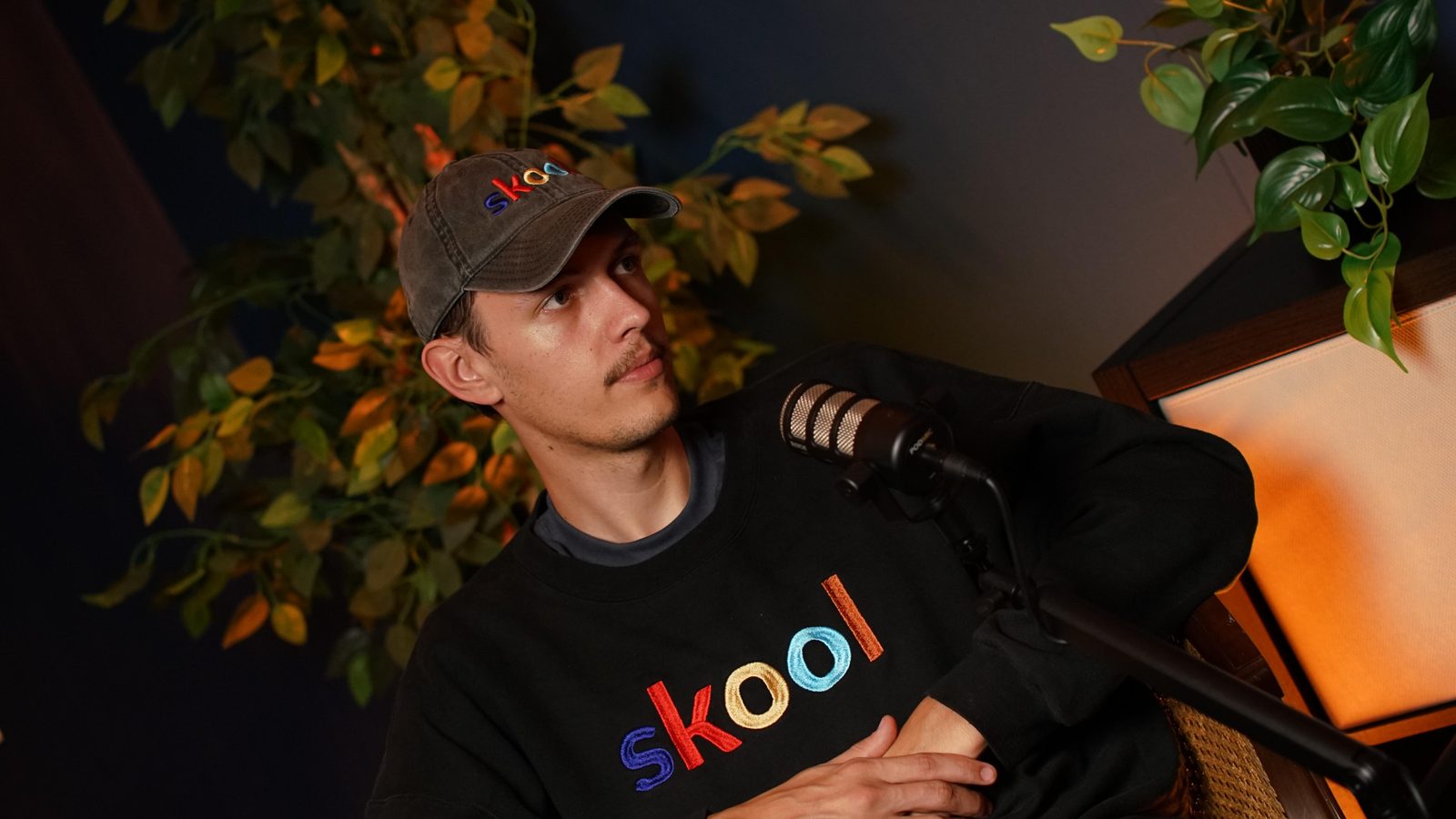 A guest in a cap and sweatshirt leaning back in the cane-back armchair at the New York set